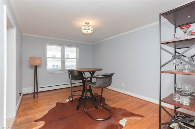 dining room featuring wood-type flooring, a baseboard radiator, and crown molding