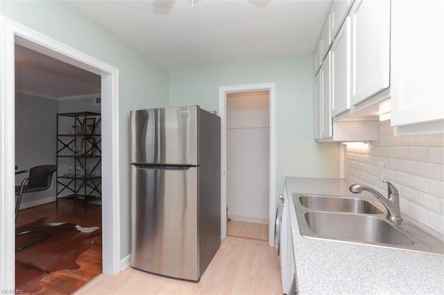 kitchen with white cabinets, stainless steel fridge, sink, and light hardwood / wood-style flooring