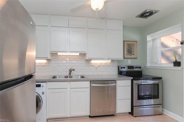 kitchen with white cabinets, stainless steel appliances, washer / clothes dryer, and sink