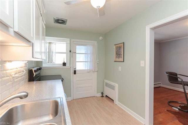 doorway to outside featuring light hardwood / wood-style floors, radiator heating unit, sink, and a baseboard heating unit