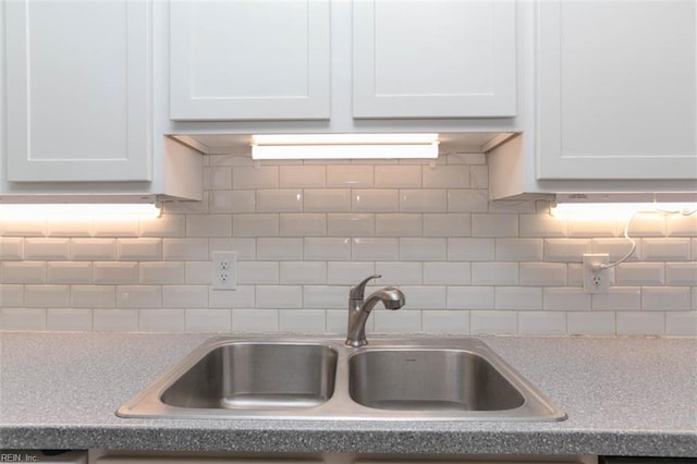 kitchen with tasteful backsplash, white cabinetry, and sink