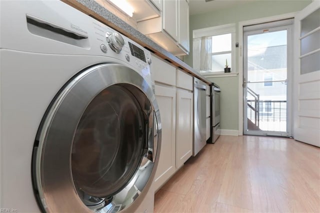 clothes washing area with cabinets, washer / dryer, and light hardwood / wood-style flooring