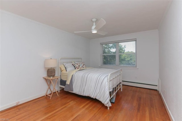 bedroom featuring ceiling fan, hardwood / wood-style floors, ornamental molding, and a baseboard heating unit