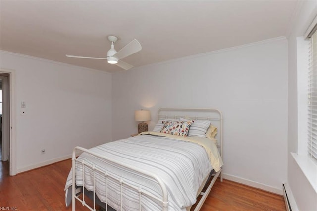 bedroom with hardwood / wood-style floors, ceiling fan, ornamental molding, and a baseboard heating unit