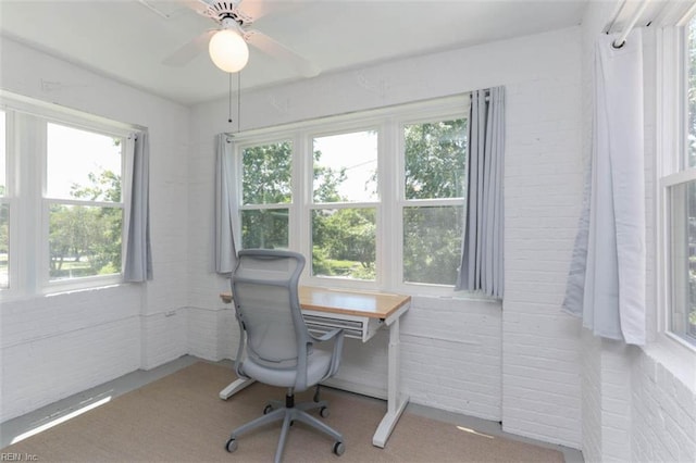 home office featuring ceiling fan, carpet floors, and brick wall