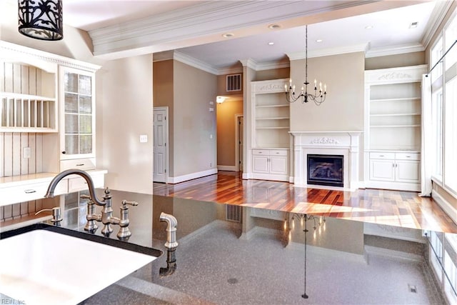 kitchen featuring sink, crown molding, a chandelier, wood-type flooring, and decorative light fixtures