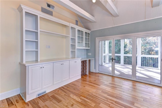 interior space with light wood-type flooring, french doors, and vaulted ceiling with beams