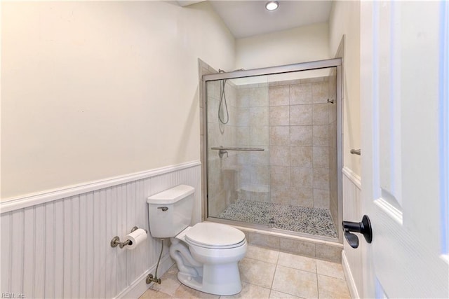 bathroom featuring tile patterned floors, toilet, and a shower with door