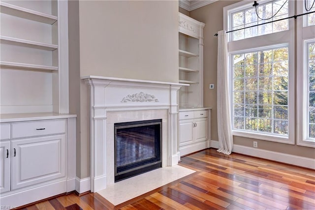 unfurnished living room featuring an inviting chandelier, ornamental molding, and light wood-type flooring