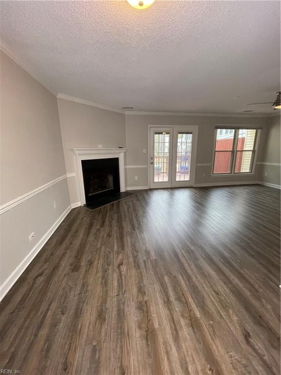 unfurnished living room with a textured ceiling, crown molding, and dark wood-type flooring