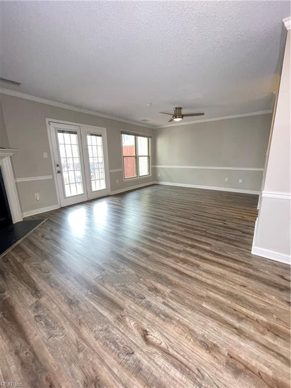 unfurnished living room featuring ceiling fan, dark wood-type flooring, a textured ceiling, and ornamental molding