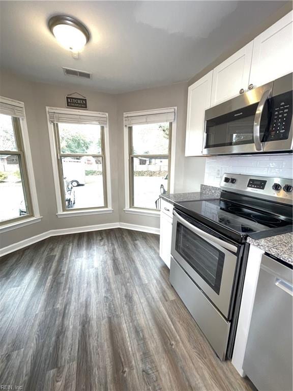 kitchen featuring dark hardwood / wood-style flooring, plenty of natural light, white cabinets, and stainless steel appliances