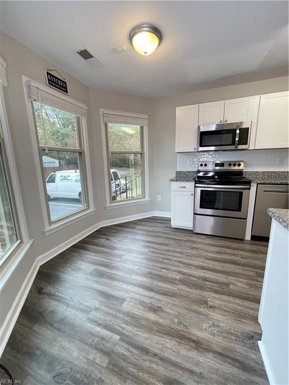 kitchen with stone countertops, dark hardwood / wood-style flooring, white cabinetry, and appliances with stainless steel finishes