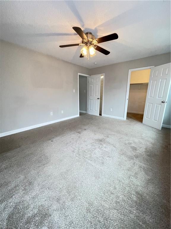 unfurnished bedroom featuring carpet flooring, ceiling fan, a spacious closet, a textured ceiling, and a closet