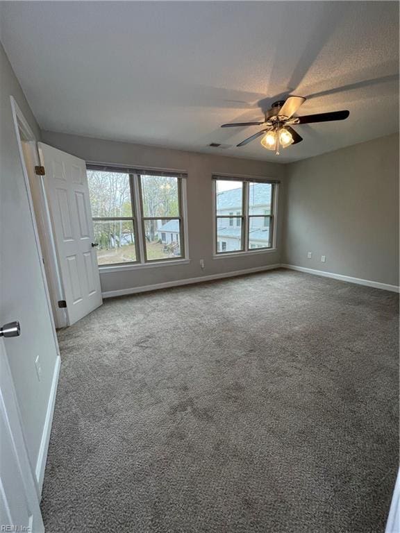 spare room with dark colored carpet and ceiling fan