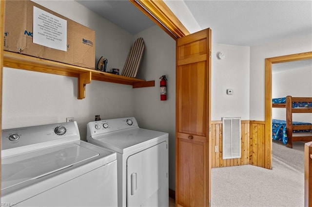 laundry area with washer and clothes dryer, wood walls, and carpet