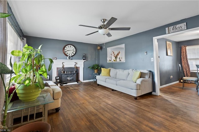 living room with dark hardwood / wood-style flooring, a brick fireplace, and ceiling fan