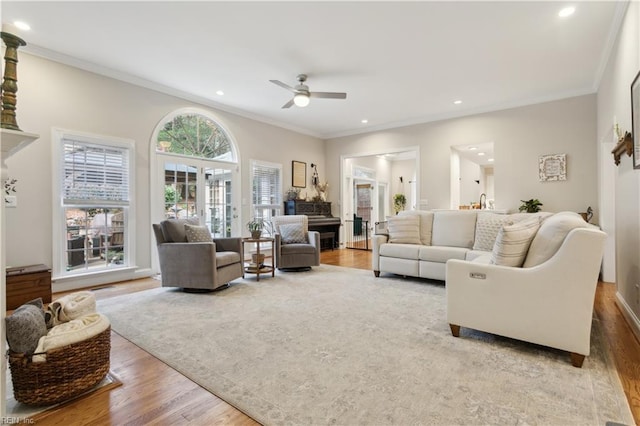 living room featuring hardwood / wood-style floors, ceiling fan, and ornamental molding