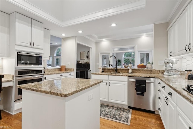 kitchen with kitchen peninsula, light hardwood / wood-style flooring, a kitchen island, white cabinetry, and stainless steel appliances