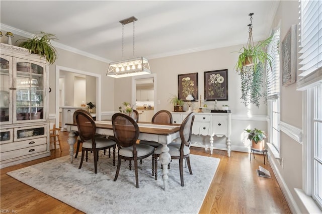 dining area featuring plenty of natural light, ornamental molding, and light wood-type flooring