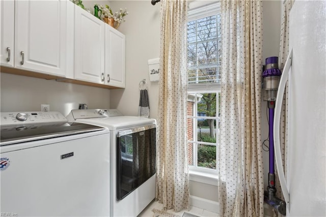 clothes washing area featuring washing machine and clothes dryer and cabinets