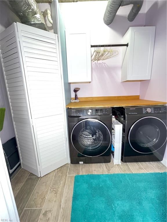 laundry area with washing machine and dryer, light hardwood / wood-style flooring, and cabinets