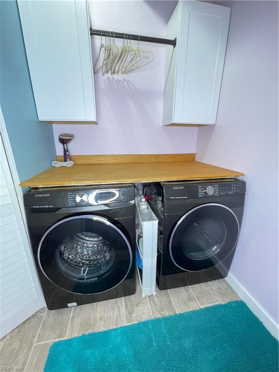 laundry area with cabinets, light wood-type flooring, and washer and clothes dryer