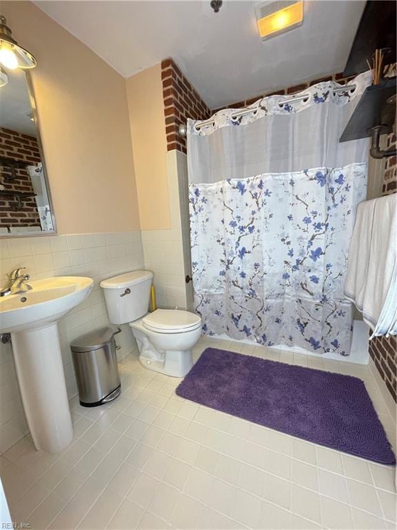 bathroom featuring sink, tile walls, tile patterned flooring, toilet, and curtained shower