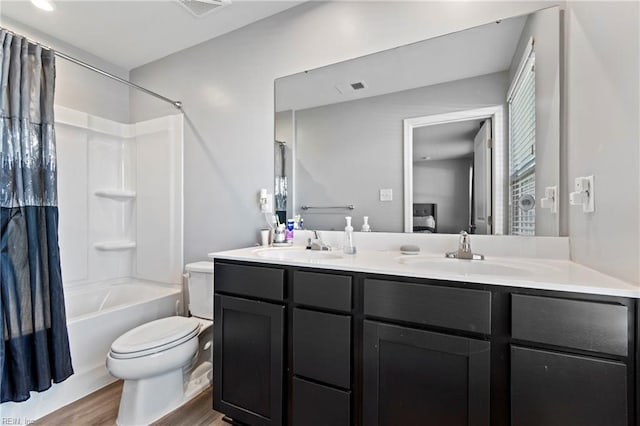 full bathroom with wood-type flooring, vanity, shower / tub combo, and toilet