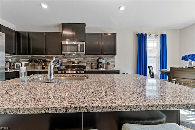 kitchen with tasteful backsplash, sink, an island with sink, and appliances with stainless steel finishes