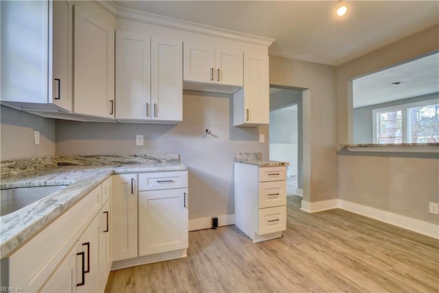 kitchen with white cabinets, light hardwood / wood-style floors, light stone countertops, and sink