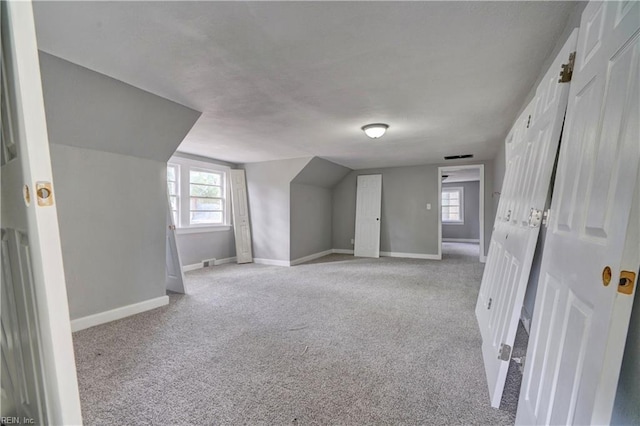 additional living space with plenty of natural light, light colored carpet, and lofted ceiling