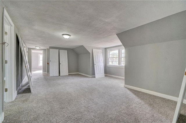 additional living space with light colored carpet, lofted ceiling, and a textured ceiling