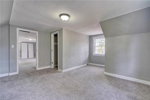 bonus room featuring a textured ceiling, light colored carpet, and vaulted ceiling