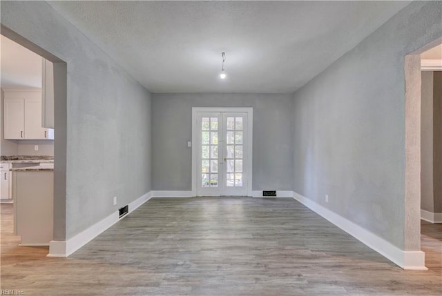 unfurnished dining area featuring french doors and light hardwood / wood-style floors