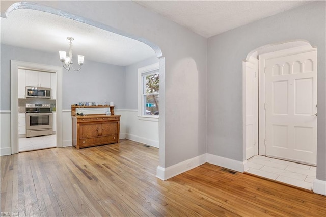 interior space featuring light hardwood / wood-style flooring, a chandelier, and a textured ceiling