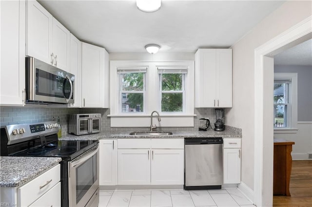 kitchen with white cabinets, sink, stainless steel appliances, and a wealth of natural light