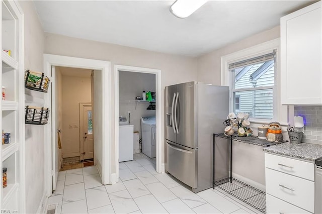 kitchen with decorative backsplash, stainless steel fridge, light stone countertops, independent washer and dryer, and white cabinetry