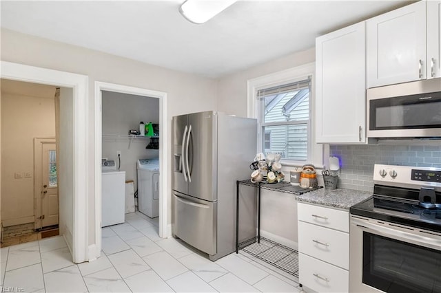 kitchen with light stone countertops, white cabinets, washer and dryer, and appliances with stainless steel finishes