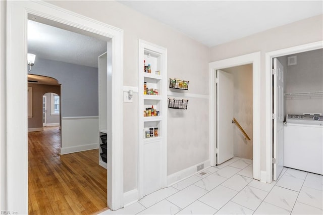 interior space featuring light wood-type flooring, a textured ceiling, and washer / clothes dryer