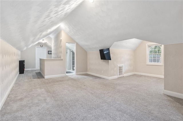 additional living space with light colored carpet and vaulted ceiling