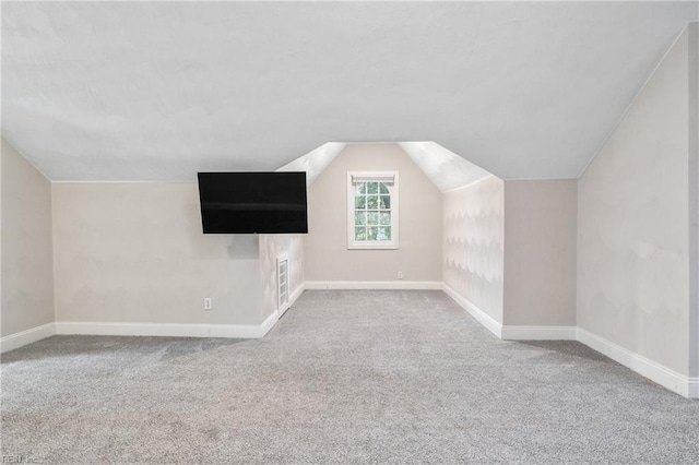 additional living space featuring light carpet and vaulted ceiling