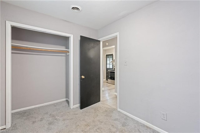 unfurnished bedroom with light carpet and a closet