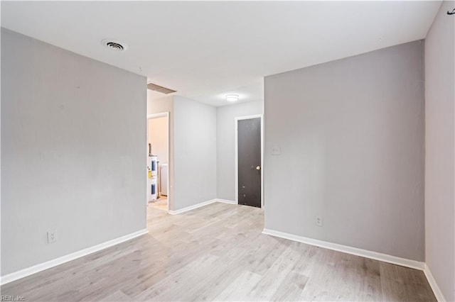 spare room featuring light wood-type flooring and electric water heater