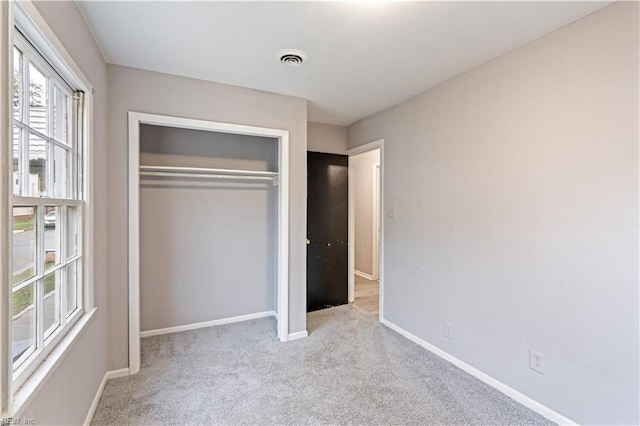 unfurnished bedroom featuring light colored carpet and a closet