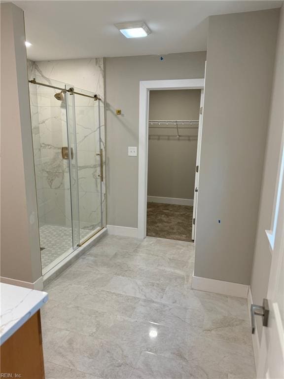 bathroom featuring a shower with door and vanity