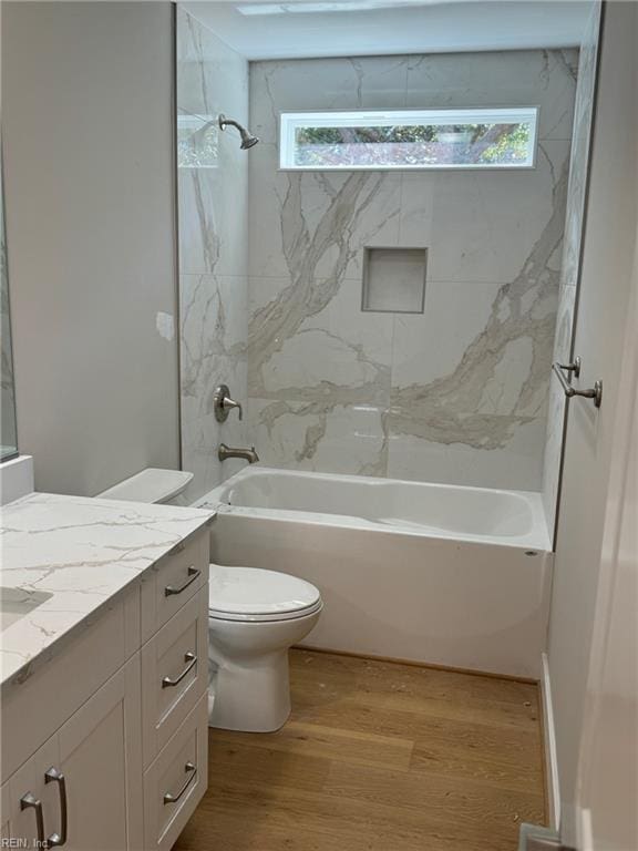 full bathroom featuring hardwood / wood-style floors, vanity, tiled shower / bath, and a wealth of natural light