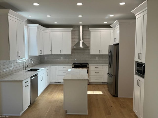 kitchen with white cabinets, a kitchen island, wall chimney range hood, and stainless steel appliances