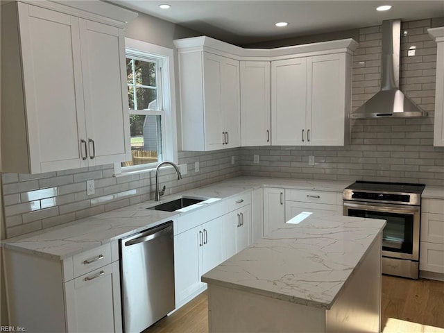 kitchen featuring white cabinets, wall chimney exhaust hood, sink, and appliances with stainless steel finishes