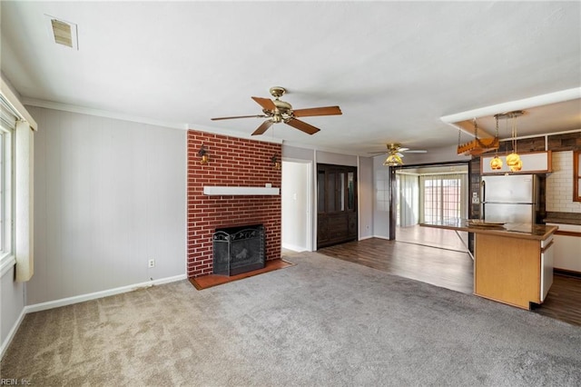 unfurnished living room with crown molding, ceiling fan, dark hardwood / wood-style floors, and a brick fireplace